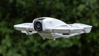 DJI Neo voalndo delante de un árbol