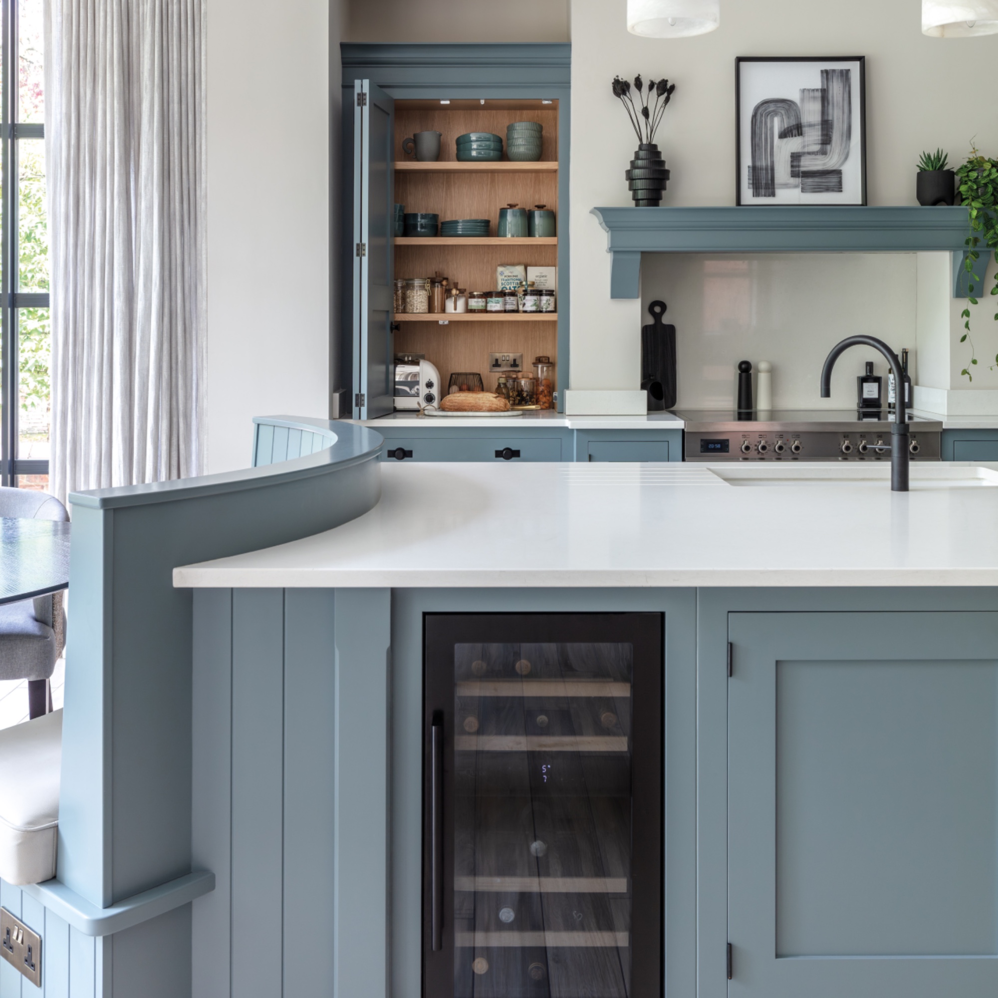 blue kitchen with banquette seating, globe lights, storage solutions, large kitchen island