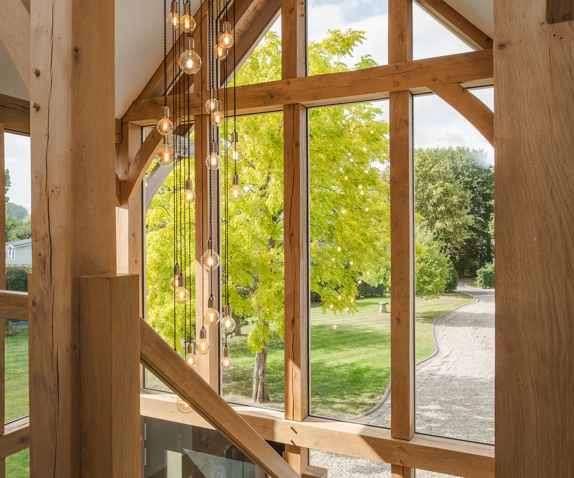 Double height glazing framed with oak beams and statement lighting pendants