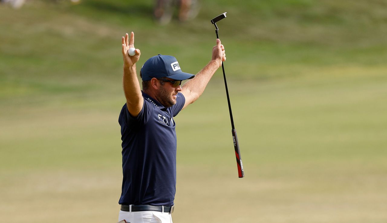 Conners holds his hands up in the air after securing victory