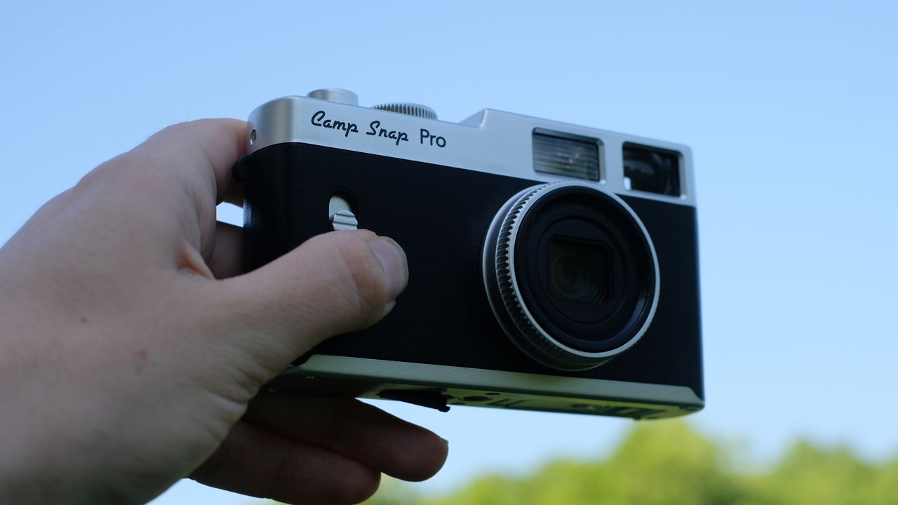 Photograph of Camp Snap CS-Pro digital compact camera held up against blue sky in one hand