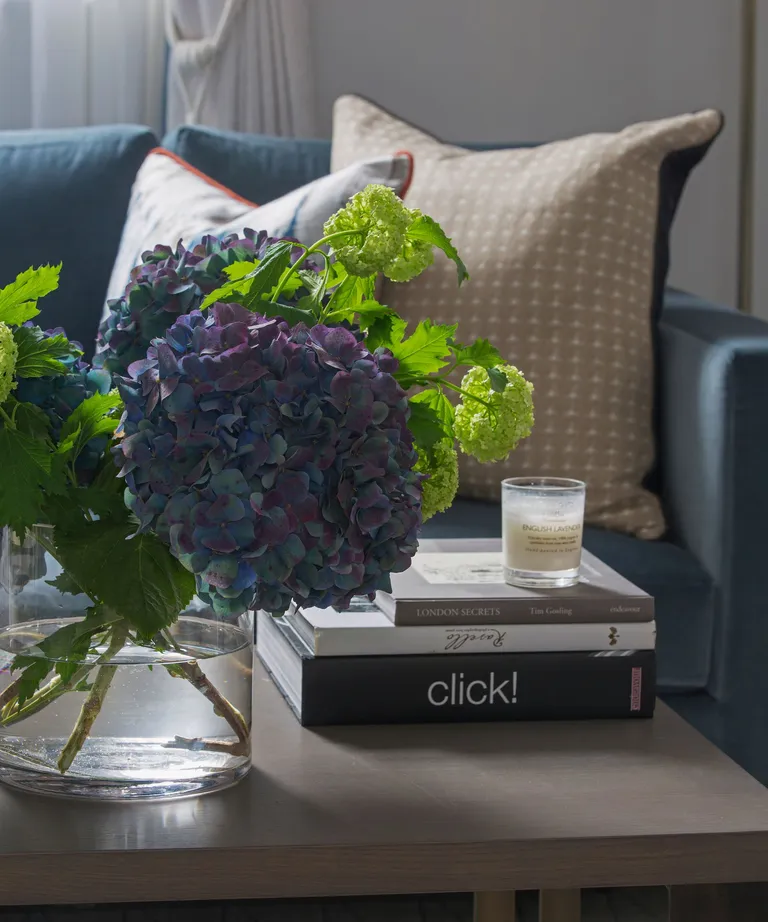 Sitting room coffee table and vase with flowers, sofa and cushions.