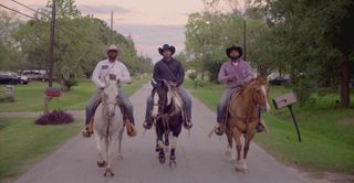 three cowboys on horseback riding through a street in the doc god save texas