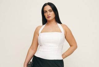 Woman wears white Reformation plus-size halter top with black maxi skirt