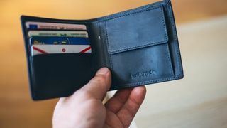 a wallet opened in a man's hand, revealing cards