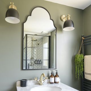 green bathroom with ornate mirror and wall lights