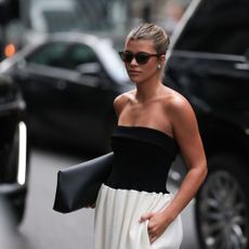 Sofia Richie wearing a black, strapless top, white skirt and sunglasses in New York