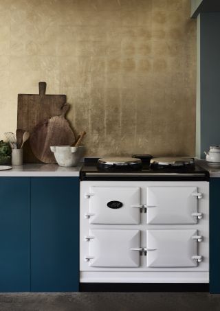 Blue kitchen ideas in a scheme with chalk painted kitchen base cabinets, a white Aga and gold leaf backsplash.