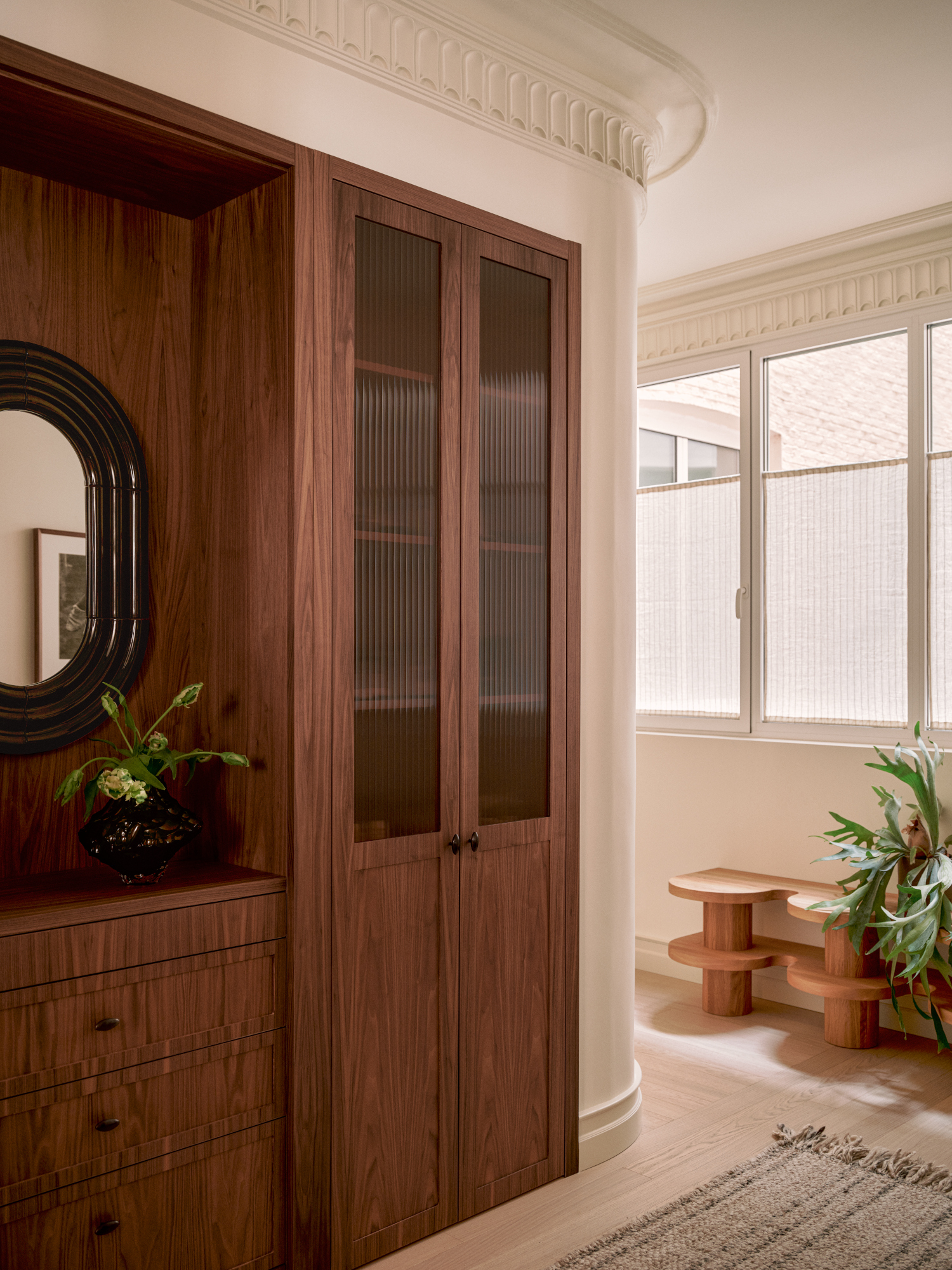 Rounded corner of a room with deep wood cabinetry with fluted glass