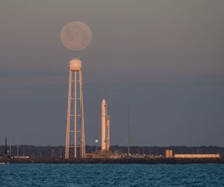 The full moon appears to hover over Pad-0A of NASA's Wallops Flight Facility at dawn on Feb. 9, 2020 where a Northrop Grumman Antares rocket and Cygnus cargo ship stood ready for a launch attempt to the International Space Station.