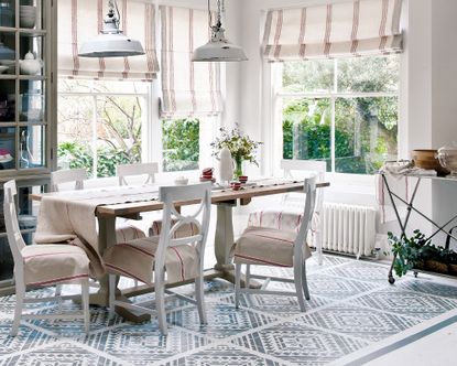 Vinyl kitchen flooring ideas, kitchen diner with patterned blue vinyl flooring, wooden dining table with white dining chairs, white painted walls with red and cream striped blinds