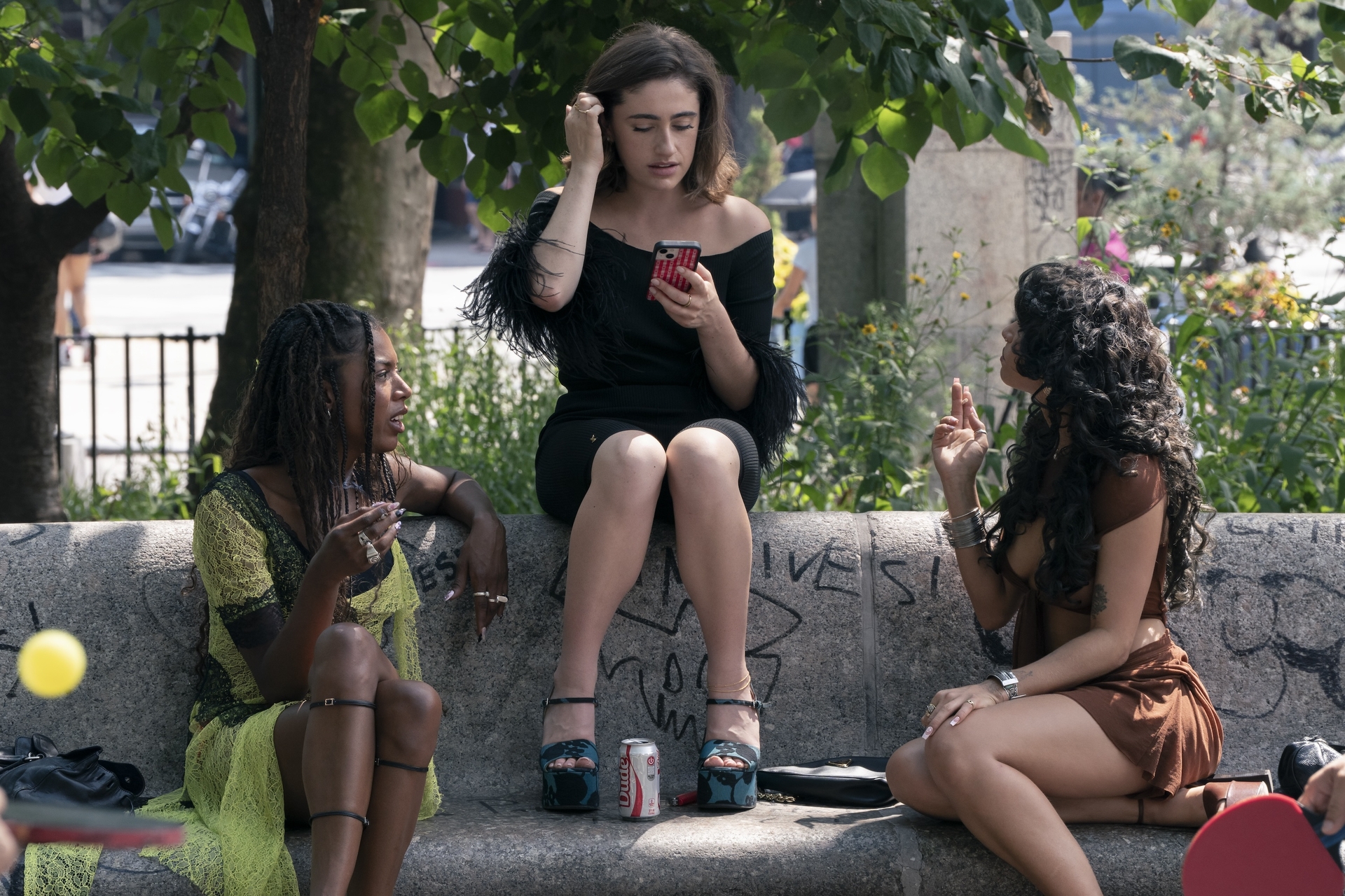 True Whitaker, Rachel Sennott, and Odessa A&amp;rsquo;zion sit on a bench in new york city outside in the summer talking to each other in a still from the i love la season 1 finale
