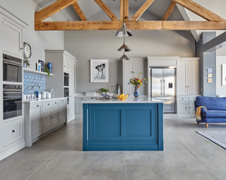 A large open plan kitchen diner with pale gray walls and a blue painted kitchen island.