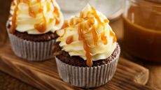 Sticky toffee cupcakes with buttercream and caramel on a wooden board