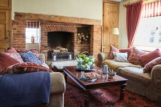 farmhouse living room with brick fireplace, wooden doorway and sofas
