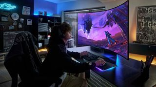 Gamer with curly hair using Samsung Odyssey Ark monitor at desk