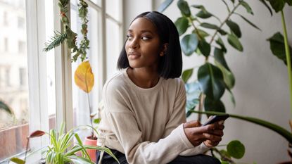 A young woman looks thoughtful as she looks out a window.