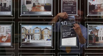 An estate agent hangs a promotional sign in the shop window