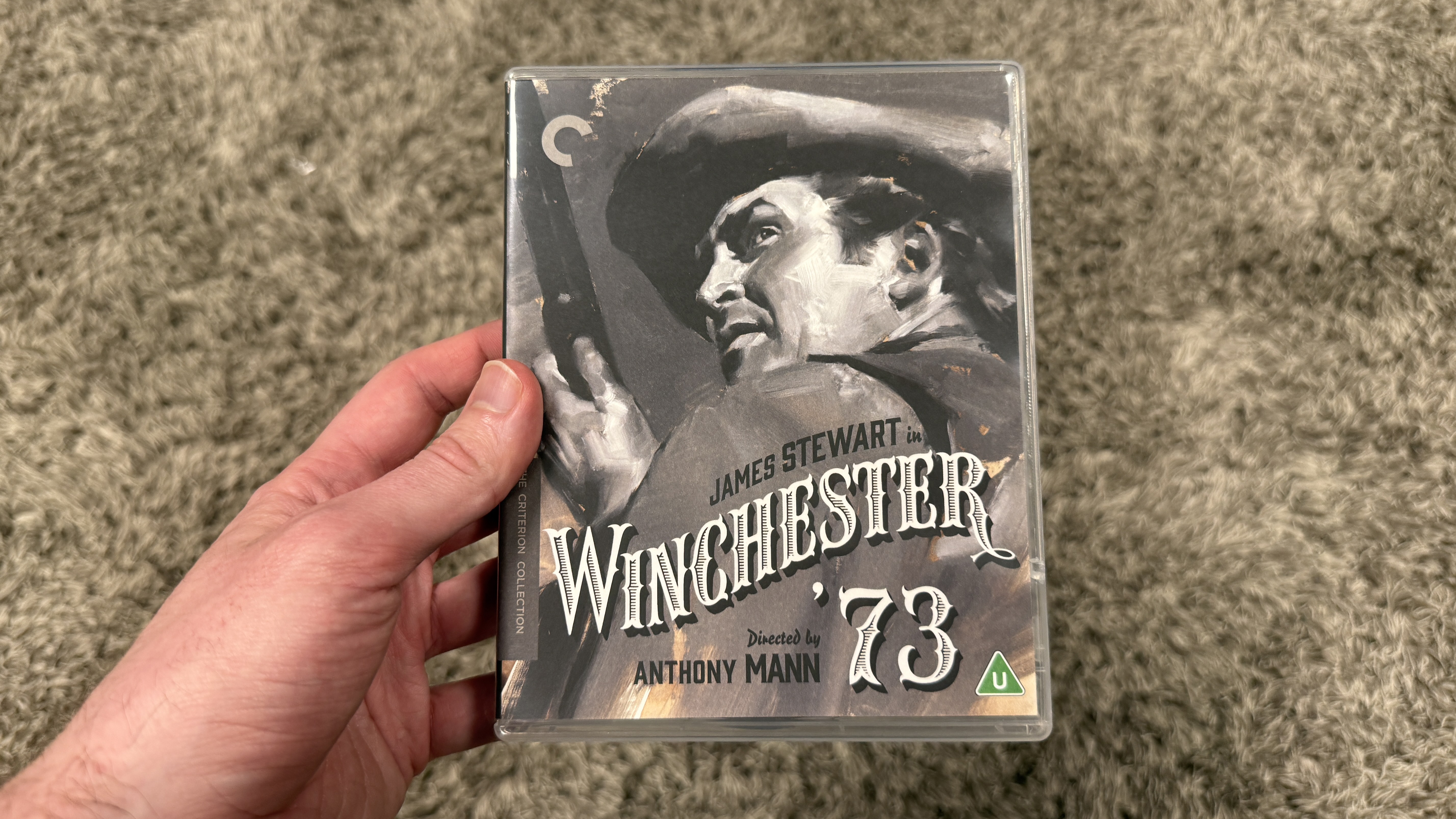 A man's hand holding the Winchester '73 Blu-ray box