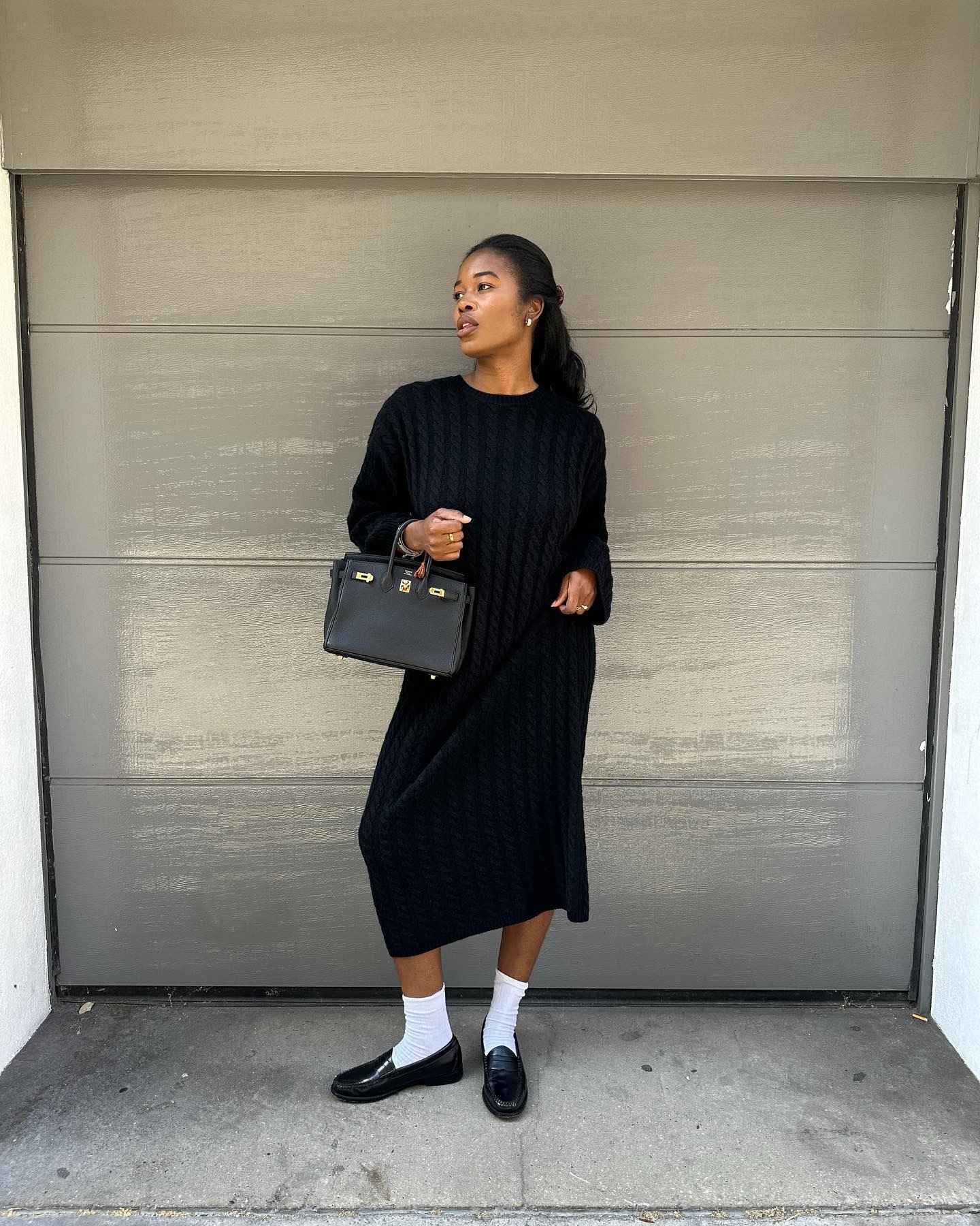 Woman wears knit dress, white socks and black loafers