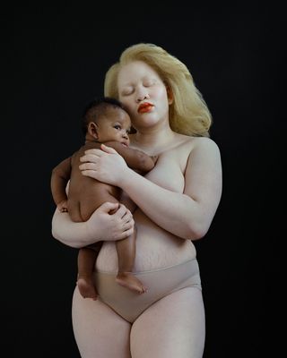 A nude woman holding a new born baby