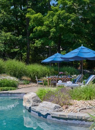 patio next to pool with loungers, table, chairs and umbrella