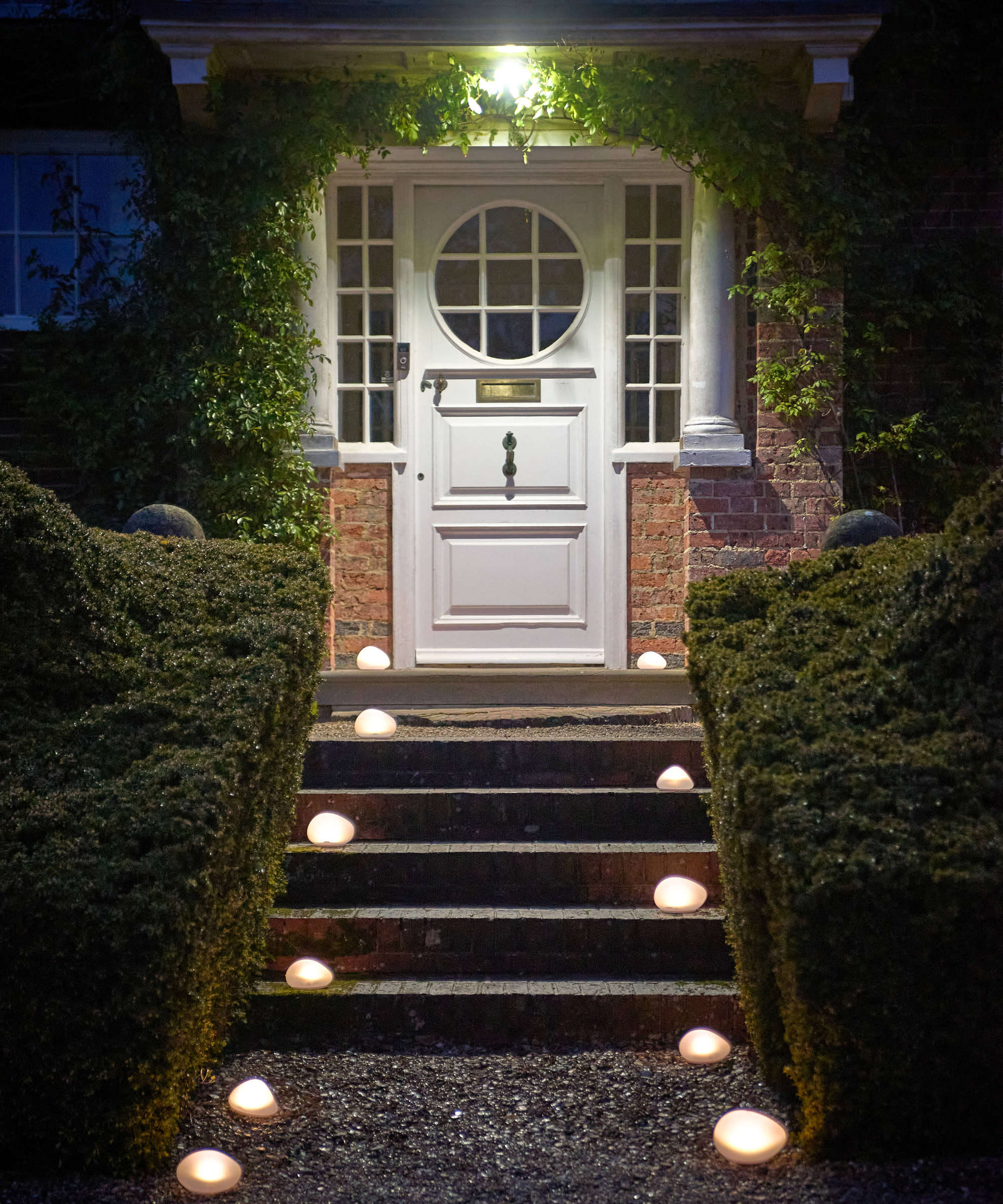 solar pebble lights placed on pathway and stairs leading to small covered porch and white front door
