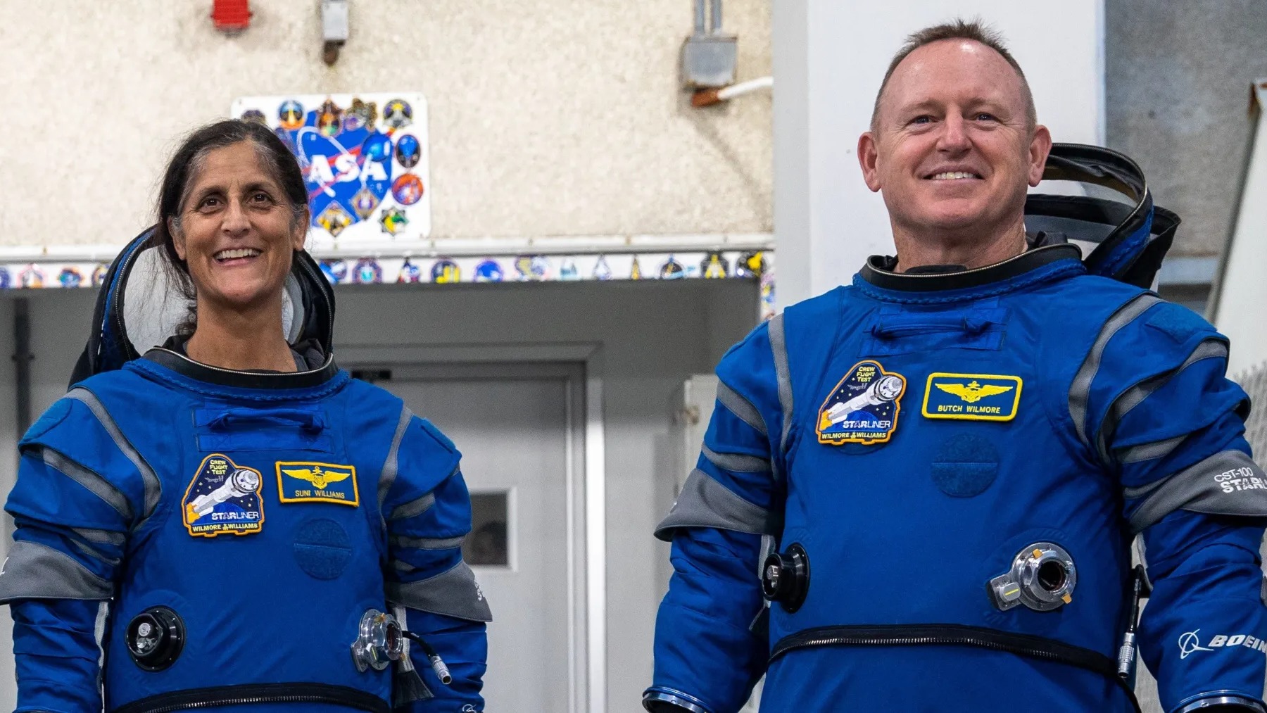deux astronautes se tiennent debout et sourient en combinaison spatiale