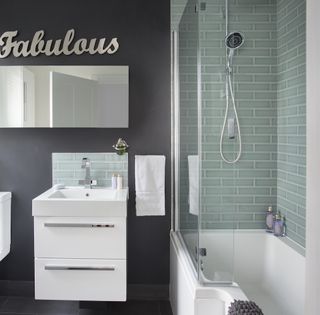 bathroom with grey and green tile wall and wash basin and bathtub