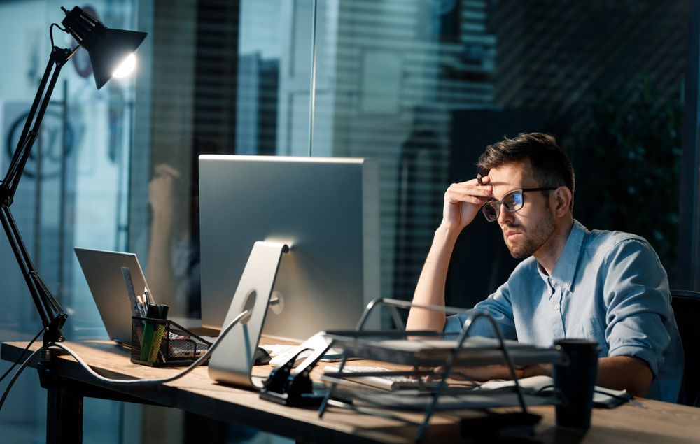 Stressed fella on a laptop in the dark