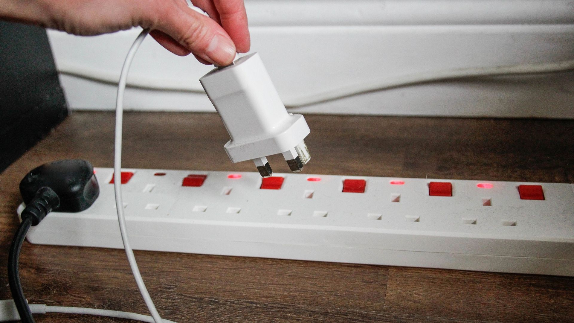 Person plugging phone charger into surge-protected power strip