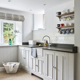 Neutral laundry room with stone floor and metro tiled splashback