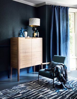 A navy blue living room with a dark toned, heavy curtains