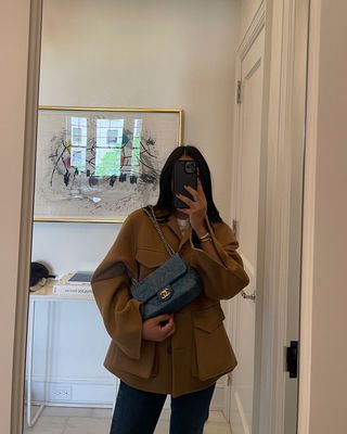 A woman taking a mirror selfie and holding a Chanel Flap bag.