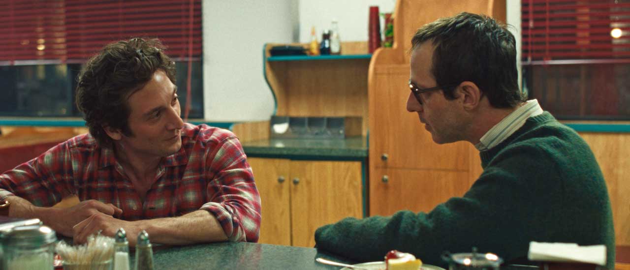 Jeremy Allen White as Bruce Springsteen and Jeremy Strong as John Landau in a diner in a scene from Deliver Me From Nowhere