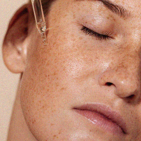 Woman holding skincare pipette to face