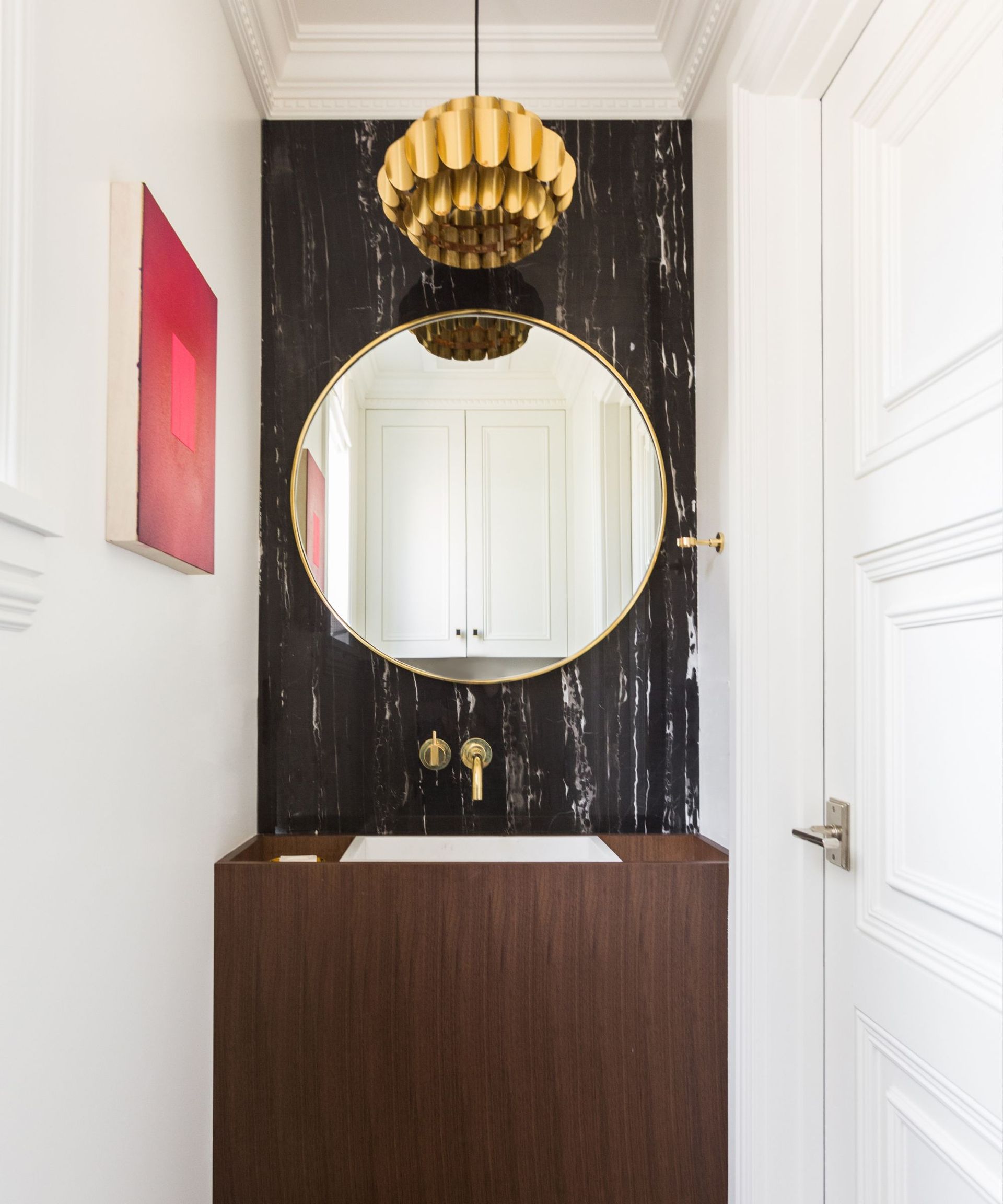 An art deco-style bathroom with a circular mirror and statement light fixture