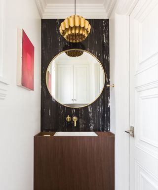 An art deco-style bathroom with a circular mirror and statement light fixture