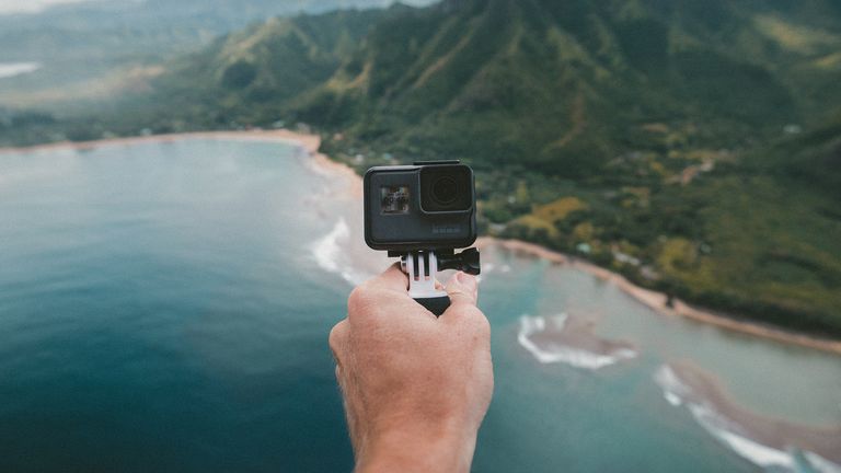 best goPro: hand holding GoPro action camera against an island backdrop