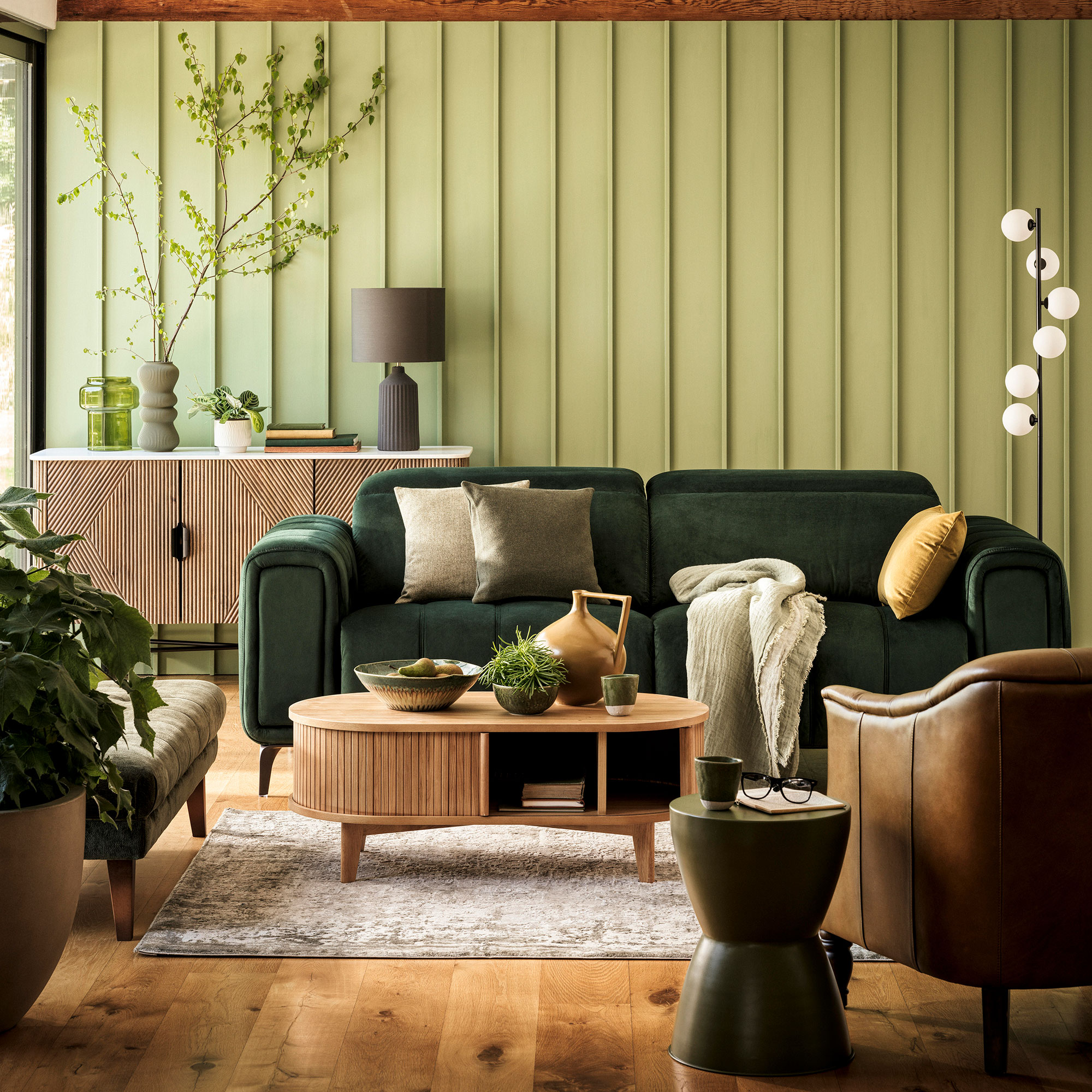 Living room with green panelled walls and green velvet sofa