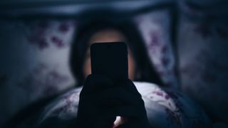 woman playing on her phone in bed