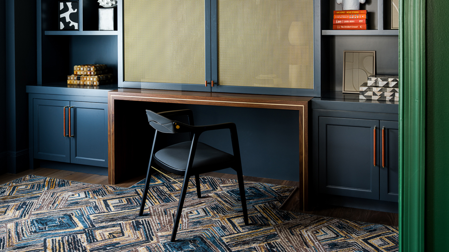 home office with blue joinery, black chair and patterned rug