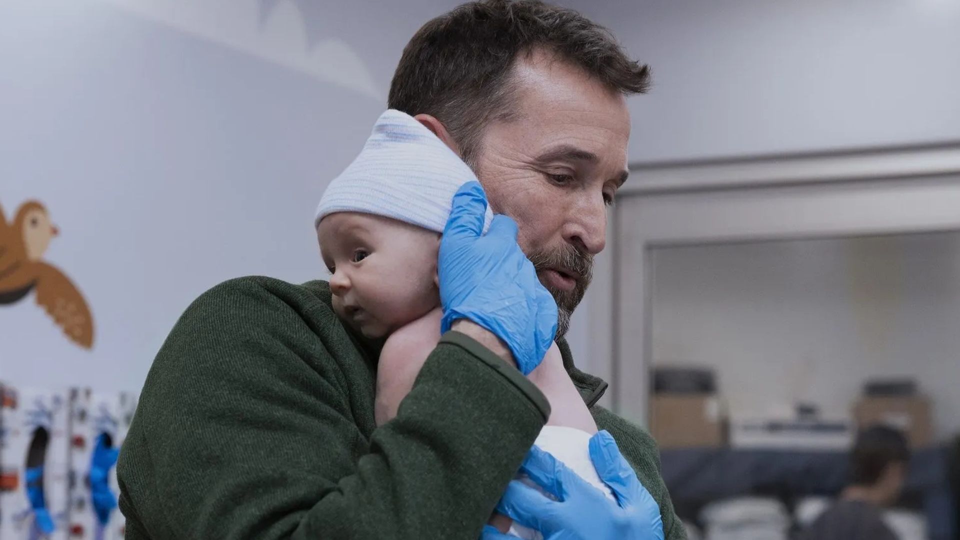 Dr. Robby cradles a baby into his chest