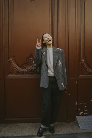 A Paris Fashion week guest wearing a gray blazer, white shirt, blue jeans, and loafers