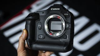 Canon EOS R1 mirrorless camera in the hand with a basketball court background, under the lights