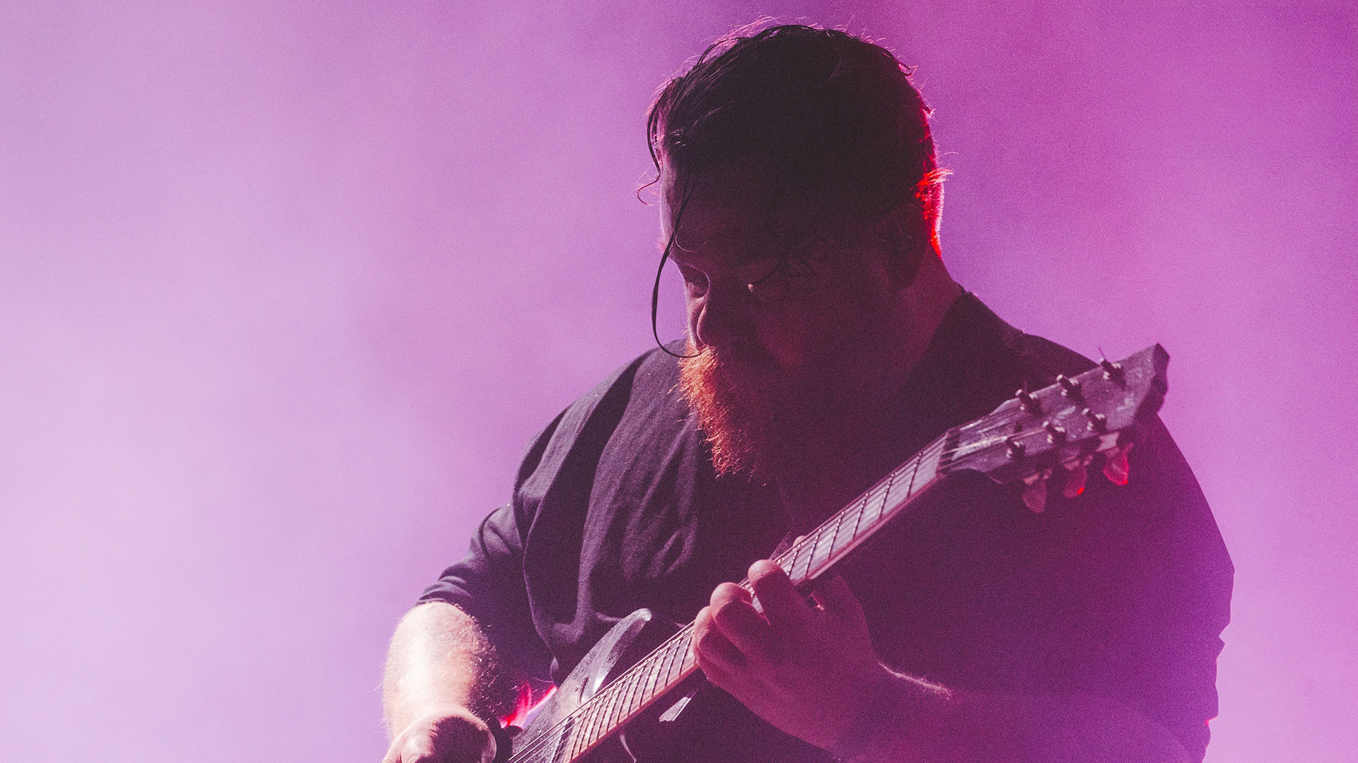 We Lost The Sea Guitarist Mark Owen onstage, against a purple back light