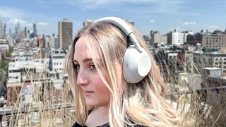 A woman wearing white Sony WH-1000XM6 noise-cancelling headphones