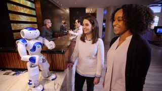 Two women in a hotel lobby talking to an AI robot
