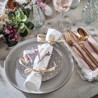 A dining table set for Christmas dinner with a homemade Christmas cracker set on top of plates