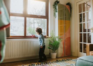 A child playing beside a radiator inside a home